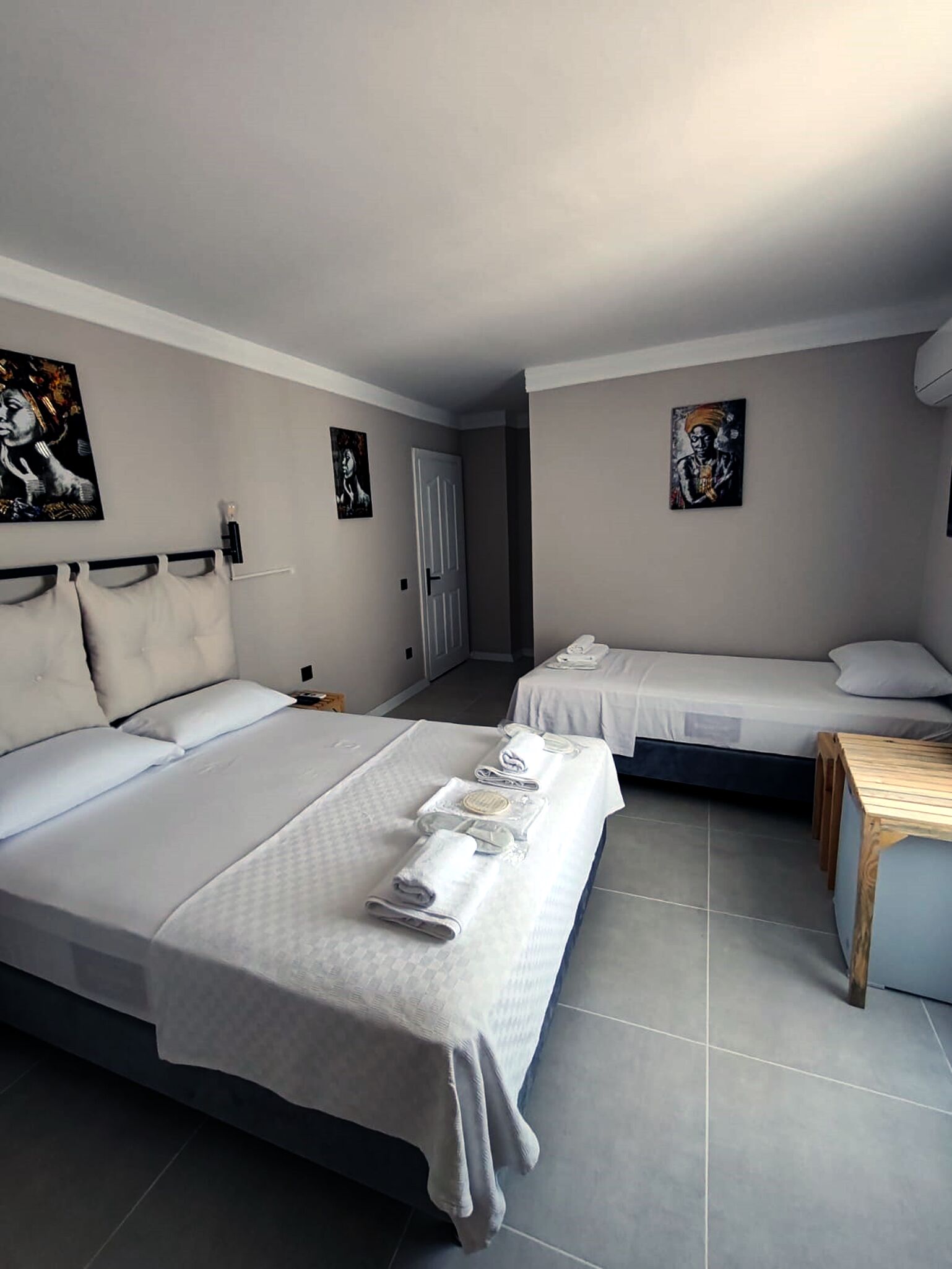 Habitación de hotel con dos camas, una mesita de madera y obras de arte en las paredes.