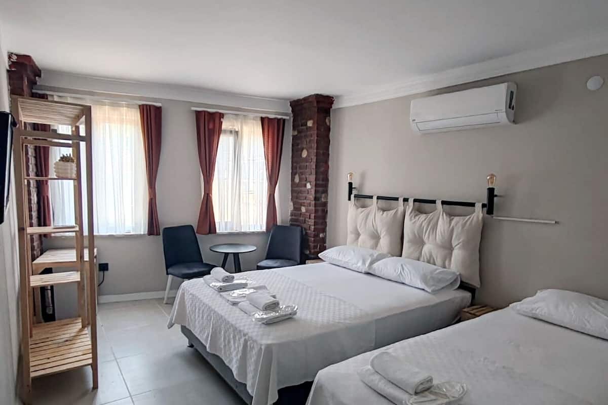 A hotel room with two beds, a wooden shelf, a desk, and a chair.