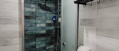 A modern bathroom with a glass shower enclosure, a toilet, and a towel rack.