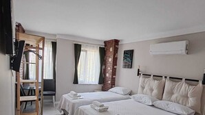Ein Hotelzimmer mit zwei Betten, einem Holztisch, einem Fernseher und einer Klimaanlage.