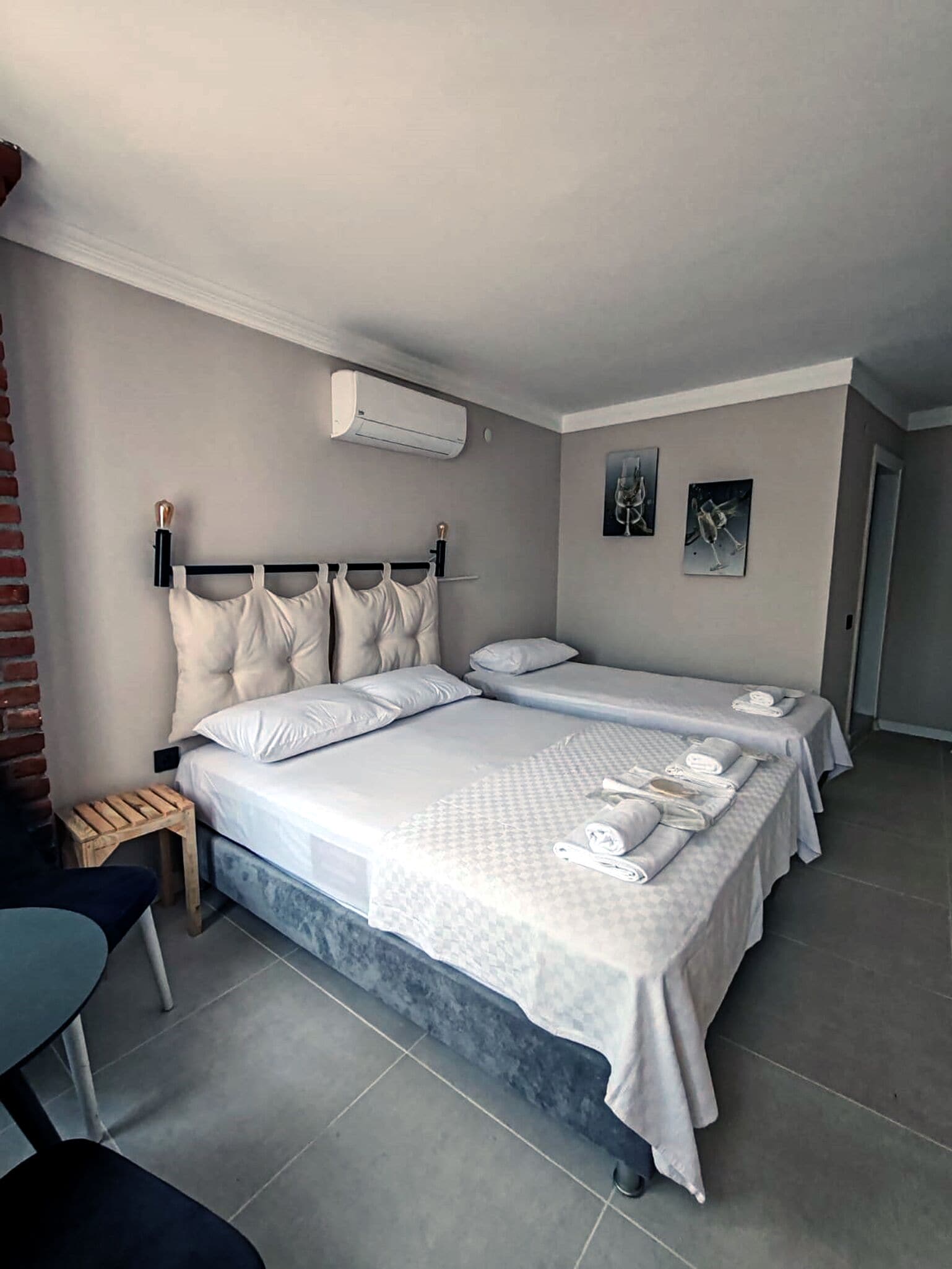 A hotel room with a large bed, two bedside tables, a small wooden stool, and a chair.