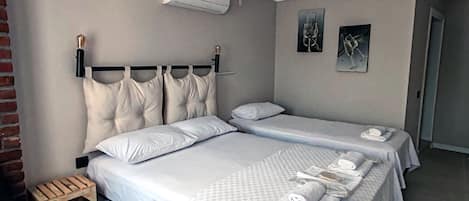 A hotel room with a large bed, two bedside tables, a small wooden stool, and a chair.