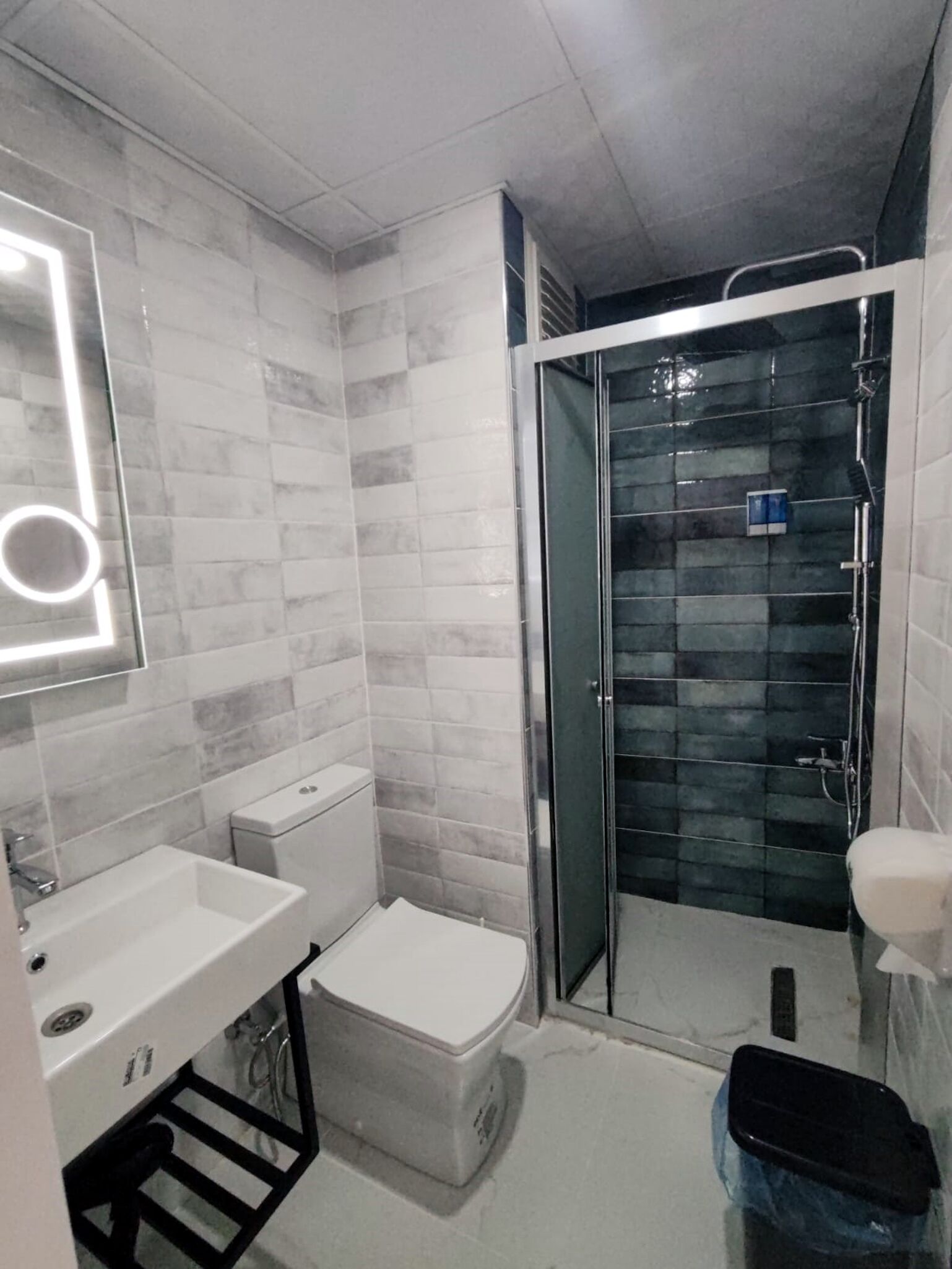 A bathroom with a white sink, toilet, and shower area.