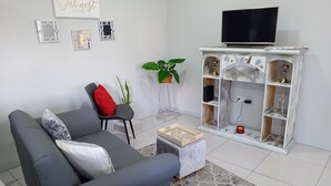 A modern living room with a grey sofa, a small coffee table, and a TV on a white cabinet. - Charming 2-bedroom apartment with WiFi, AC in lovely St David's
 (Saint David)