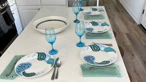 A kitchen with a white countertop, a sink, and a microwave. There are plates, glasses, and cutlery on the counter. - Beauty and The Bay (Bay St. Louis)