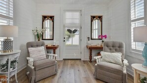 A room with two armchairs, a wooden door, and a small table with a lamp. - Beauty and The Bay (Bay St. Louis)
