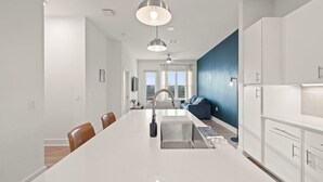 Une cuisine moderne dotée d’un îlot central, de meubles blancs et de luminaires suspendus.