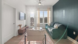 Un salon avec un canapé vert, une table basse ronde et un ventilateur de plafond.