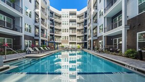 A modern multi-story building with a central swimming pool, surrounded by balconies and outdoor seating areas. - Bright, Spacious 2BD in heart of Tampa | Free Prkg (Tampa)