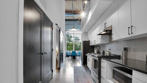 A modern kitchen with white cabinets, a black countertop, and a hexagonal backsplash. - Warm, Cozy 2BD | Pool | Gym | Central! (Greenville)