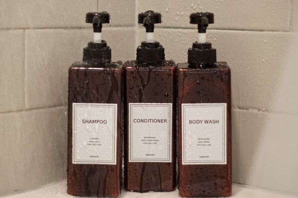 Three bottles of liquid soap labeled shampoo, conditioner, and body wash.