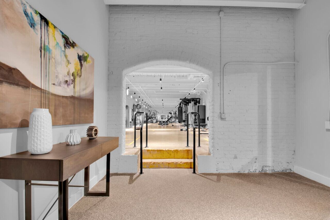 An interior space with a white brick wall, a wooden table with decorative items, and an arched doorway leading to another room.
