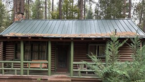 A rustic log cabin with a porch, a bench, and a small front door. - Cabin #8 - Ranch House (Payson)