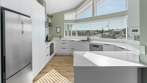 Eine moderne Küche mit weißen Schränken, einem Edelstahl-Kühlschrank und einem großen Fenster mit Blick auf die Stadtlandschaft.