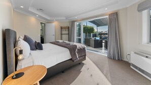 Ein modernes Hotelzimmer mit einem großen Bett, einem kleinen Holztisch und Blick auf den Außenbereich.