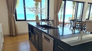 Una cocina moderna con una isla grande, suelo de madera y vistas al océano.