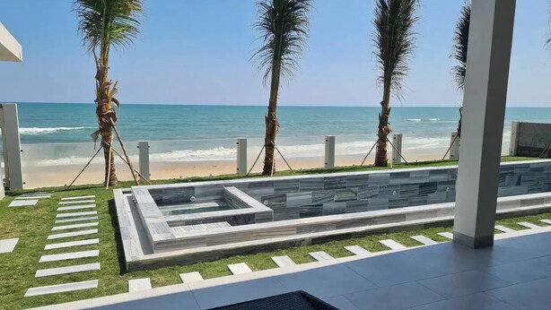 Un área de piscina moderna al aire libre con vista a la playa y al océano.
