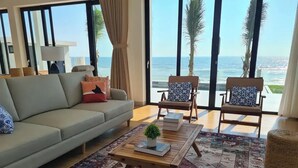 Una sala de estar con un sofá, dos sillones, una mesita de centro y vista al océano.