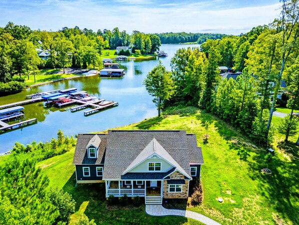 A lakeside property with a dock, boats, and a large house with a porch.