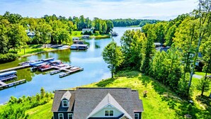 A lakeside property with a dock, boats, and a house with a porch. - Lakefront Lake Anna, Hot Tub, Pool, Beach (Mineral)