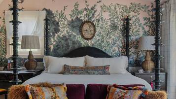 Un dormitorio con cama, sofá, candelabro y pared con un diseño de hojas.
