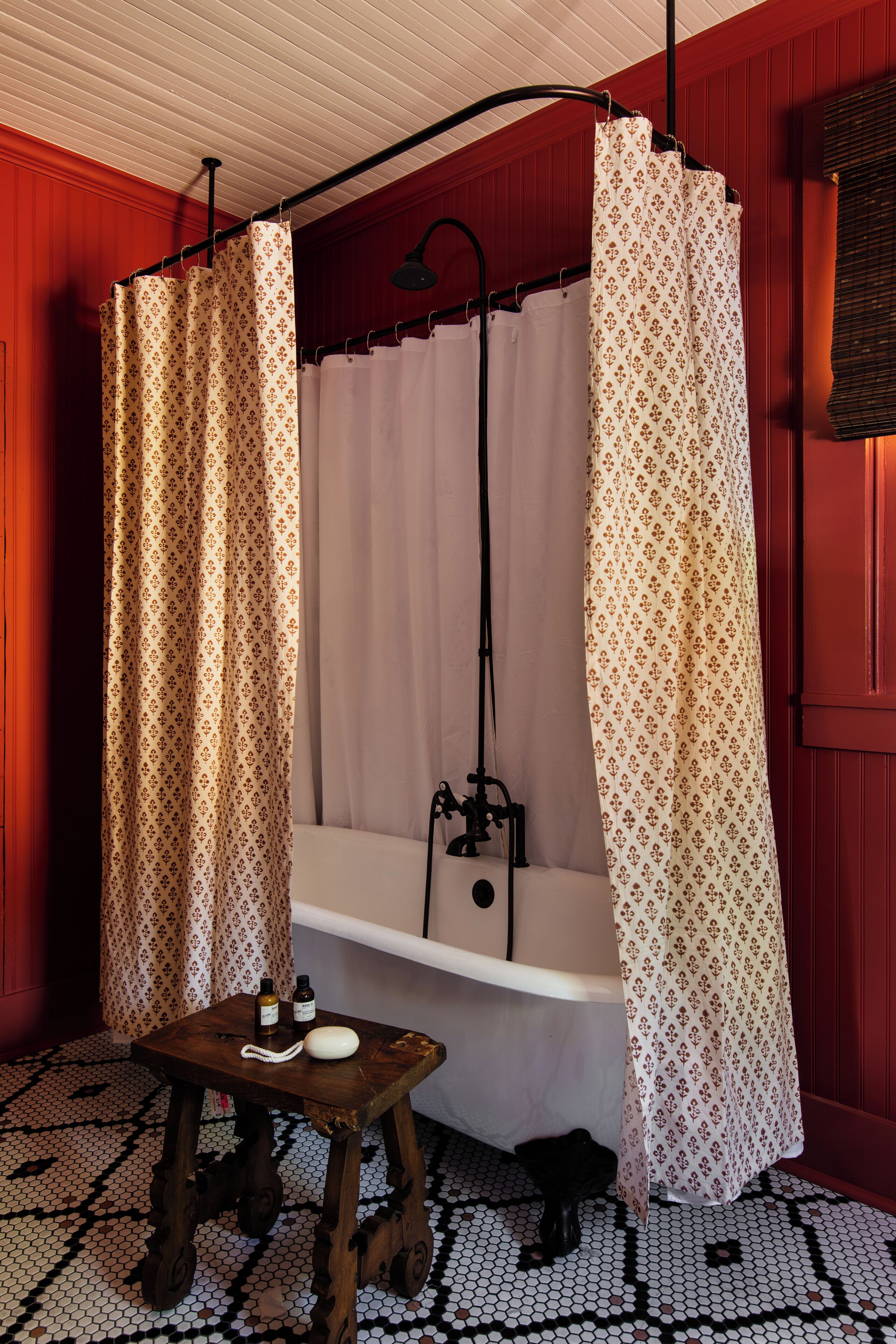 Un baño con una bañera, un taburete de madera y una cortina de ducha.