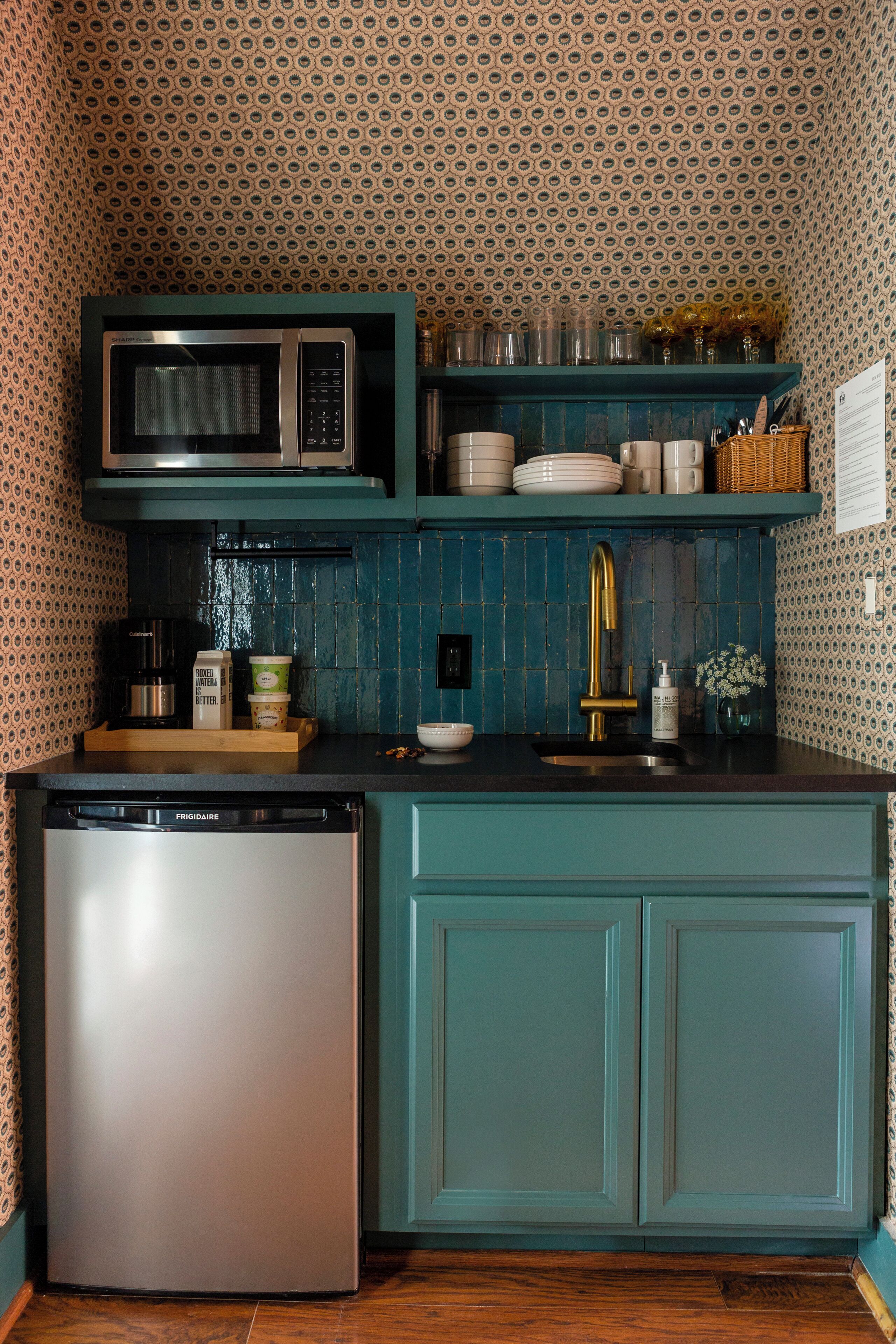 Une cuisine dotée de meubles de couleur turquoise, d’un four à micro-ondes, d’une machine à café et d’un lave-vaisselle.