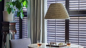 A room with a round wooden table, two chairs, a chessboard, a lamp, and a potted plant. - The Menagerie (Fredericksburg)