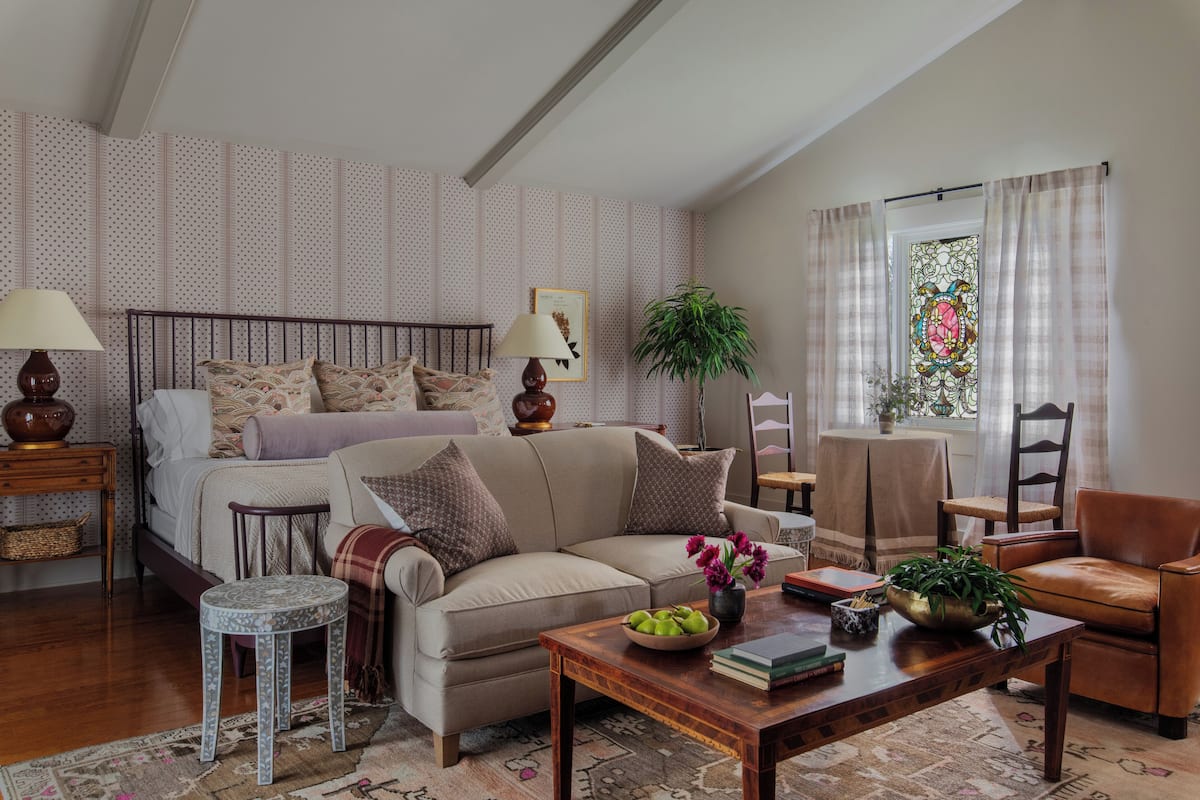 Une chambre confortable avec un lit, un canapé, une table basse et une fenêtre avec des rideaux.