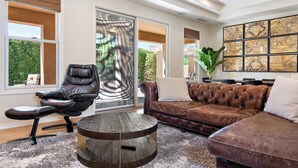 Ein modernes Wohnzimmer mit einem Ledersessel, einem braunen Ledersofa und einem runden Holztisch.