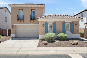 A two-story house with a garage, a balcony, and a well-maintained front yard with shrubs and rocks. - Chandler Keep – Medieval Spanish Villa, BBQ Courtyard & Prime South Chandler (Chandler)