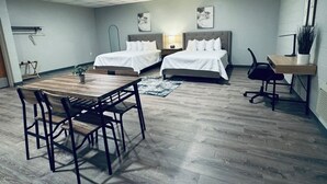 Ein modernes Hotelzimmer mit zwei Betten, einem Holzesstisch und einem Schreibtisch mit Stuhl.