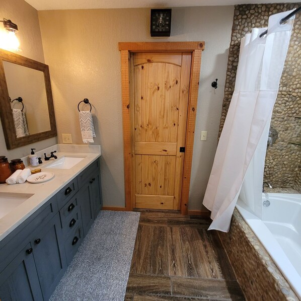 Un baño con puerta de madera, un lavabo con espejo y una bañera.