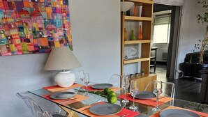 A modern dining area with a glass table, wooden chairs, and a colorful abstract painting on the wall. - Quiet 2B/1B Downtown Condo, Hills View, Bright, Spacious, Recently Remodeled (Aurillac)