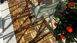 A balcony with a wooden floor, a table, chairs, and a potted plant with red flowers. - Quiet 2B/1B Downtown Condo, Hills View, Bright, Spacious, Recently Remodeled (Aurillac)