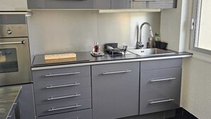 A modern kitchen with grey cabinets, a stainless steel sink, and a clock on the wall. - Quiet 2B/1B Downtown Condo, Hills View, Bright, Spacious, Recently Remodeled (Aurillac)