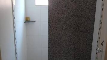 A small bathroom with a toilet, a shower enclosure, and a tiled floor.