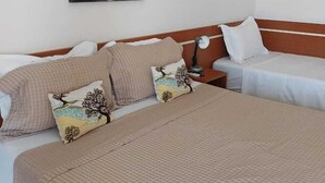Una habitación de hotel con dos camas, una mesita de noche y un cuadro colgado en la pared.