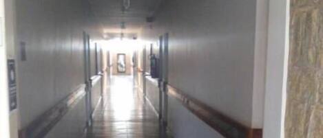 A long, narrow hallway with patterned tile flooring and white walls.