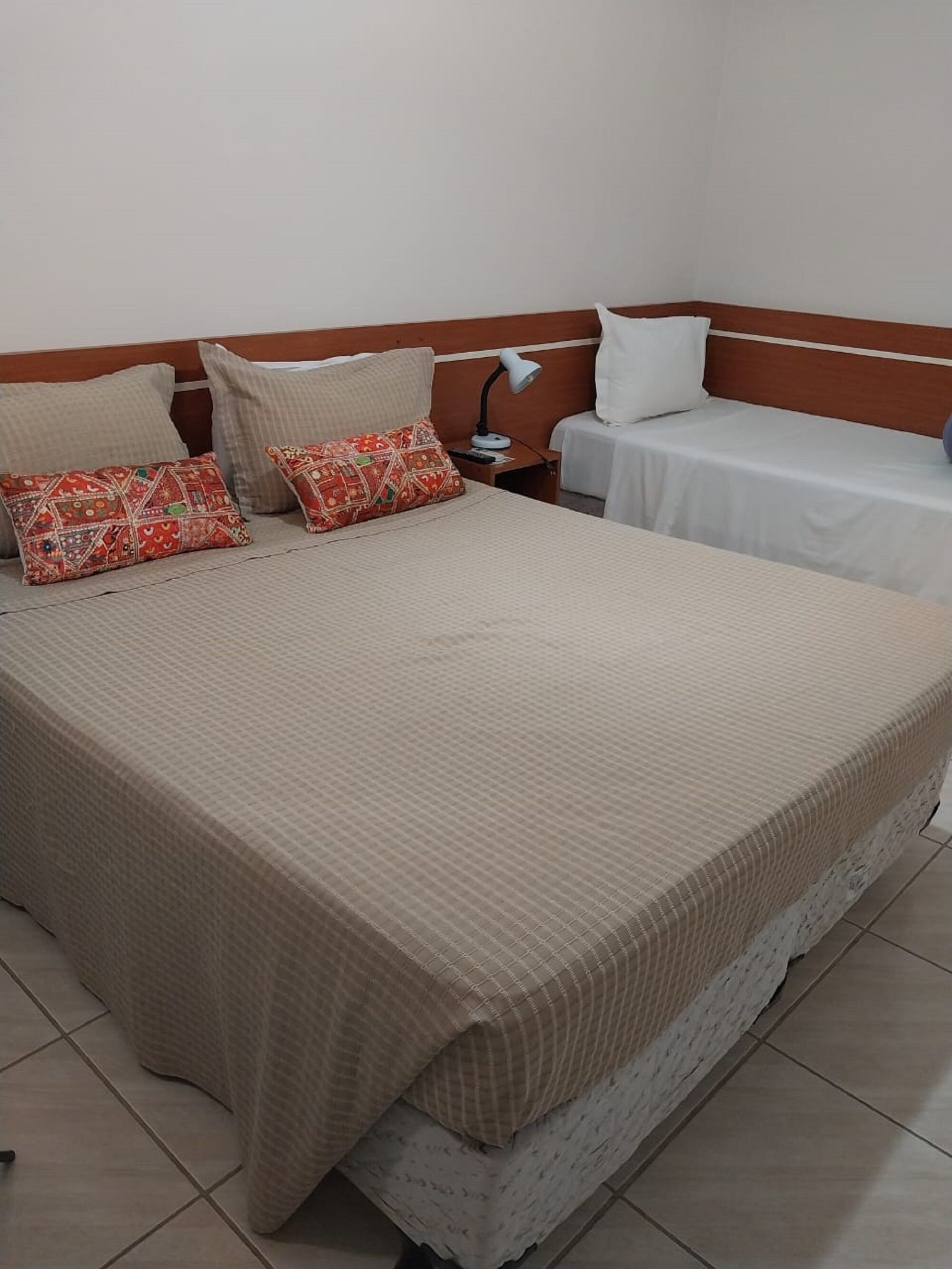 A hotel room with a large bed, two bedside tables, and a nightstand with a lamp.