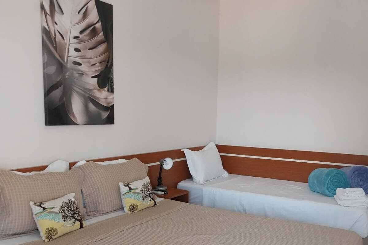 A hotel room with two beds, a large abstract painting, and a bedside lamp.