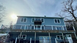 A two-story house with a balcony, a front porch, and a visible chimney. - The Place Up North (Traverse City)
