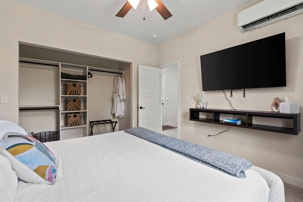 A bedroom with a bed, a wardrobe, a television, and a shelf.