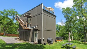 Een gebouw met twee verdiepingen, een overdekte patio, een trap en een klein buitenterrein met tafels en stoelen.