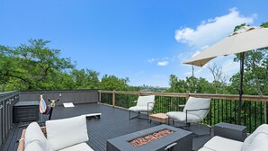 Een terras met buiten zitplaatsen, een vuurkorf en uitzicht op de stadshemel.