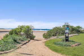 Een pad dat naar een strand leidt, met een wegwijzer op de voorgrond.
