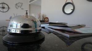 A room with a black table, a silver bell, and a stack of magazines. - Q Alacati Otel (Cesme)