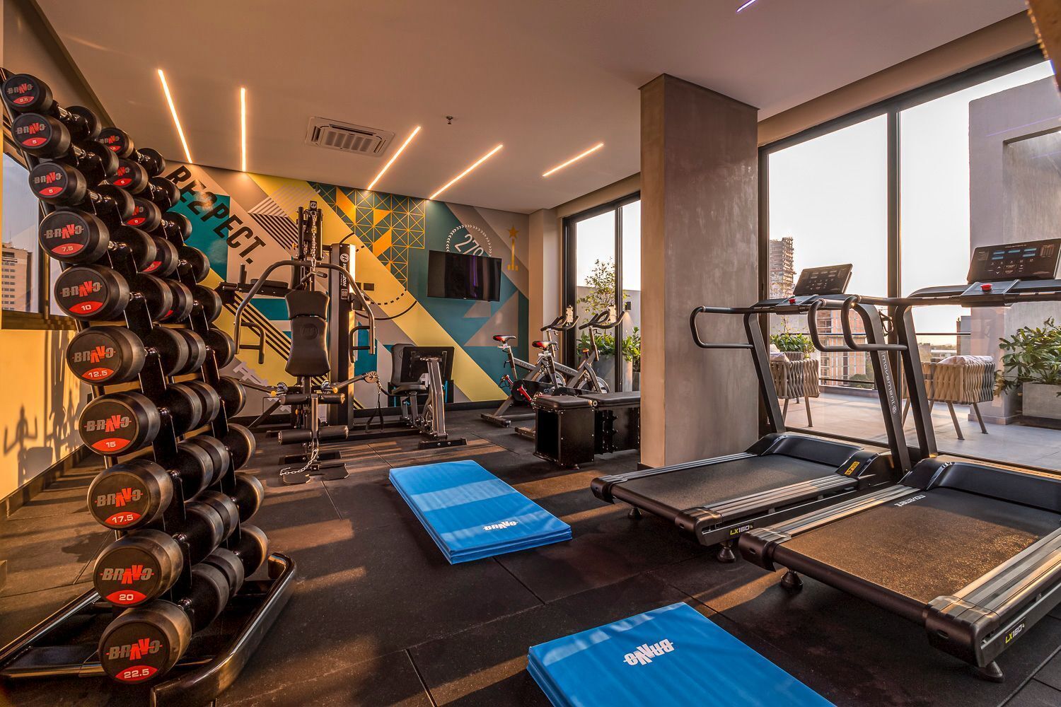 Un gimnasio moderno con diverso equipo de ejercicio, incluyendo mancuernas, una cinta de correr y una bicicleta estática.