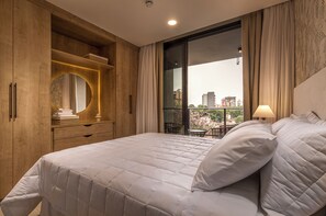 Un dormitorio con una cama grande, un armario de madera y vistas a la ciudad a través de un ventanal.