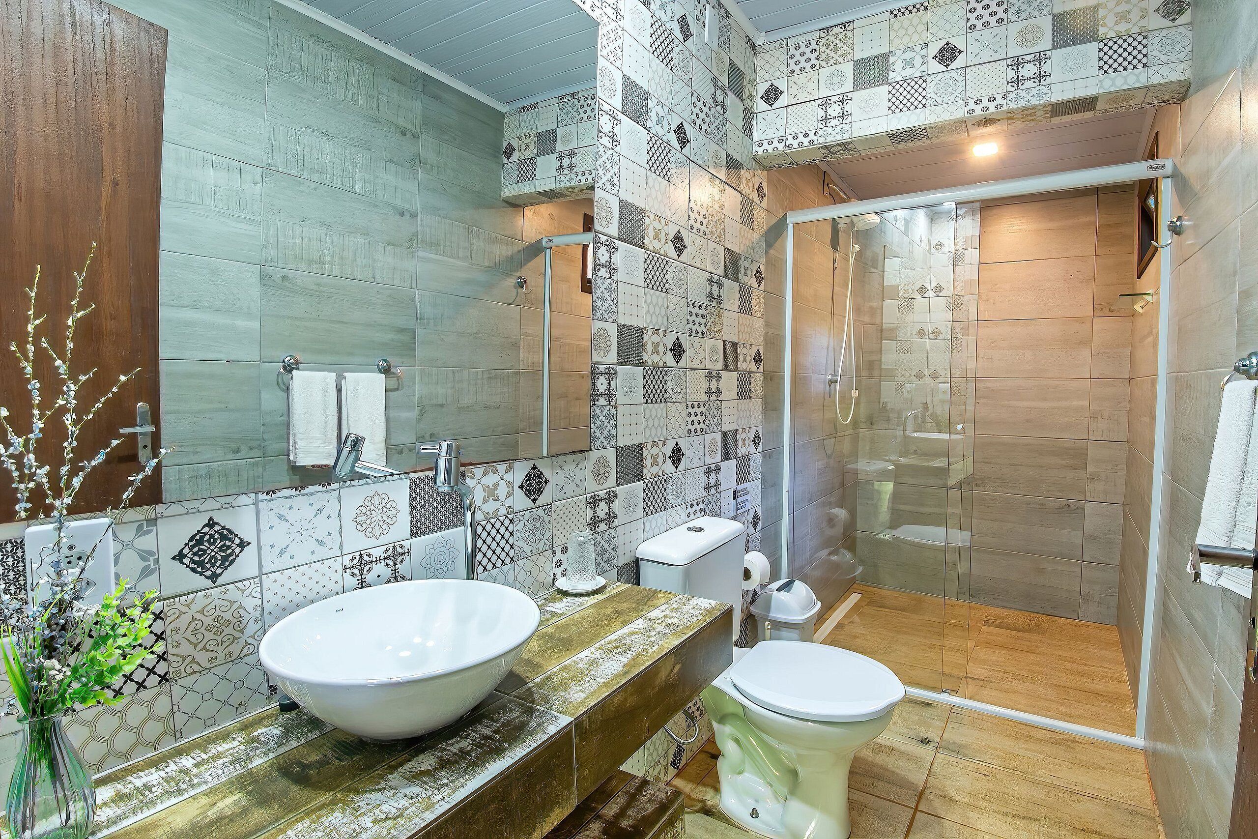 Un baño con un lavamanos grande de color blanco, un inodoro y una zona de ducha con puertas de cristal.
